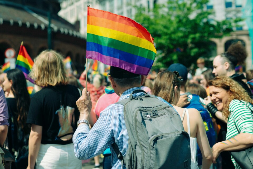 JUBILEUM: Oslo Pride fyller 50 år. I fjor gikk 90.000 personer i paraden. Bildet viser mennesker som går i prideparaden i Oslo i 2023. I fokus er en mann med ryggen til som veiver med et prideflagg i regnbuens farger.