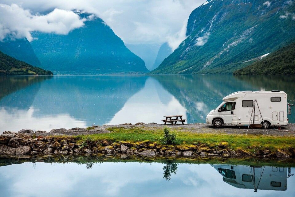 FERIE: Det har blitt billigere for utenlandske turister å reise i Norge. Bildet viser en campingbil som står parkert ved vannet i en fjord. Foto: Shutterstock/NTB