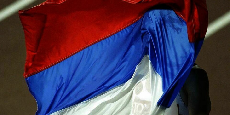 En friidretts-utøver løper med det russiske flagget. Mandag kom en stor rapport fra Verdens anti-dopingbyrå. Den viser at Russland og andre har jukset med doping.