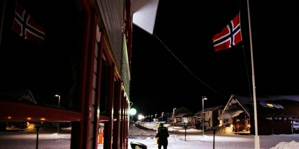 SORG:  Flagget henger på halv stang i sentrum av Longyearbyen. Få hundre meter unna kom snøskredet lørdag som traff ti hus. En mann og et barn er døde etter skredet.