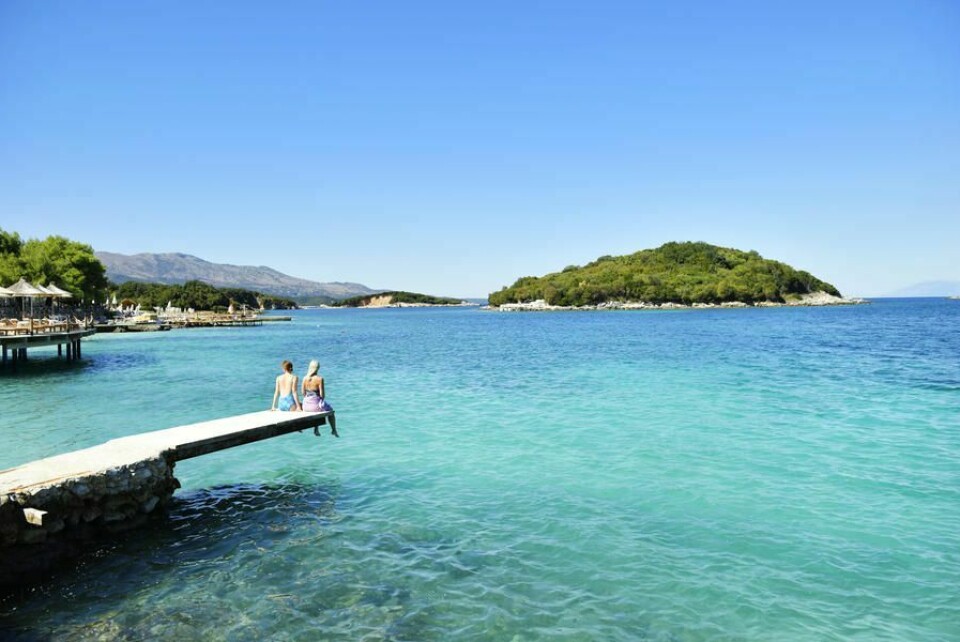 FERIE: Flest nordmenn vil til Hellas og Spania i sommerferien. Men flere vil også til land som Tyrkia, Bulgaria, Albania og Montenegro. Der får du mer verdi for pengene, skiver TUI. Bildet viser to mennesker som sitter på bryggekanten. De er på ferie.