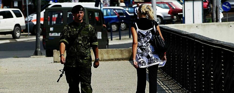 SIKKERHET: En soldat i forsvars-samarbeidet Natos gruppe i Kosovo, går på gaten i Mitrovica. Denne byen i Kosovo er delt i to av serbere og kosovo-albanere. Torsdag støttet verdens-organisasjonen FN Kosovos løsrivelse.