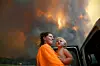 Sharnie Moren and her 18-month-old daughter Charlotte look on as thick smoke rises from bushfires near Nana Glen, near Coffs Harbour, Australia, November 12, 2019. AAP Image/Dan Peled/via REUTERS ATTENTION EDITORS - THIS IMAGE WAS PROVIDED BY A THIRD PARTY. NO RESALES. NO ARCHIVE. AUSTRALIA OUT. NEW ZEALAND OUT. TPX IMAGES OF THE DAY