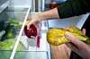 Bildet viser noen som legger frukt i kjøleskap.
