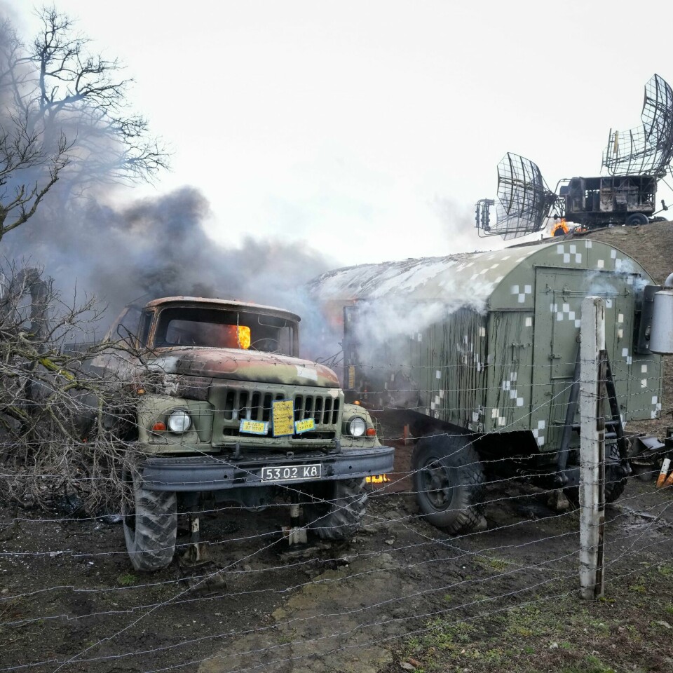 ØDELAGT: Russland har angrepet Ukraina. I første omgang har mange av målene vært militære. Flere personer skal være drept. Både soldater og sivile. Bildet er av brennende utstyr ved en radar utenfor Mariupol i Ukraina. Det er to militære kjøretøy som brenner. Foto: Sergei Grits / AP / NTB