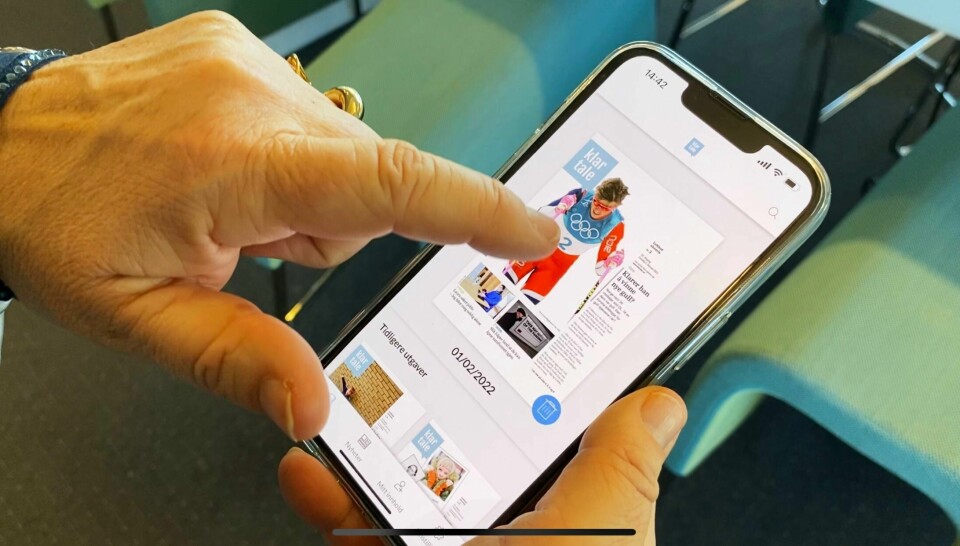 APP: Klar Tale har fått sin egen app. Med den kan du lese e-avisen og utvalgte nettnyheter. Bildet viser en hånd og e-avisen i appen på en mobiltelefon.