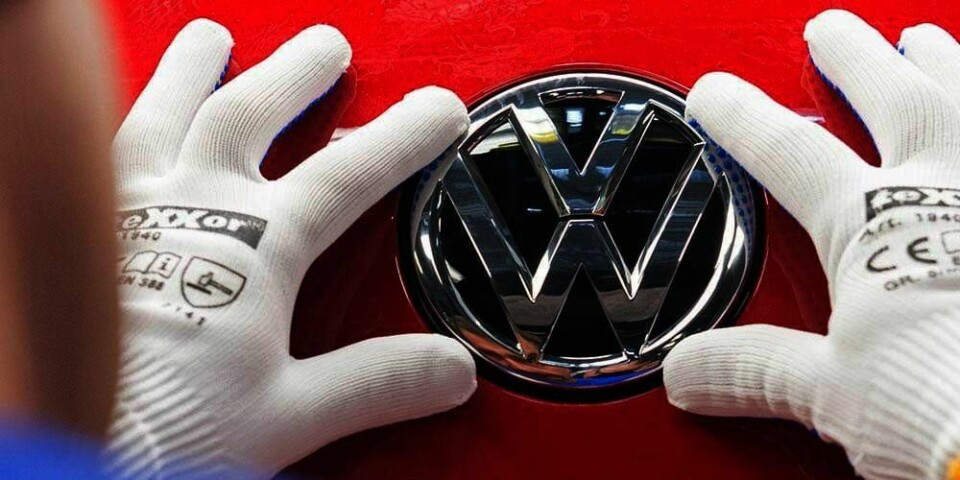 SAKSØKES: En arbeider fester merket til Volkswagen på en ny bil. Nå saksøkes bilmerket av to amerikanere. De er sinte over at bilen slipper ut mer skadelige stoffer enn de hadde trodd. Volkswagen er tatt i å ha laget et jukseprogram som skjuler utslipp fra bilene deres.