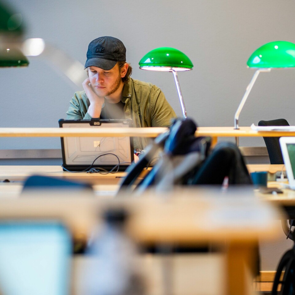 FÆRRE: Det er færre som har søkt på høyere utdanning i 2022 enn i 2021. Bildet er av en ung mann som sitter ved en pult på en lesesal. Han har på caps og sitter med en datamaskin. Foto: Håkon Mosvold Larsen / NTB