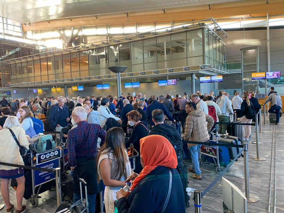 KØ: Det var lange køer på Oslo lufthavn fredag morgen. Bildet er fra Oslo lufthavn Gardermoen. Det er av folk som står i kø for å få sjekket inn bagasje. Det er teknisk trøbbel, så køene er lange. Noen folk har på munnbind. Andre er kledd for sommervær.Foto: Heiko Junge / NTB