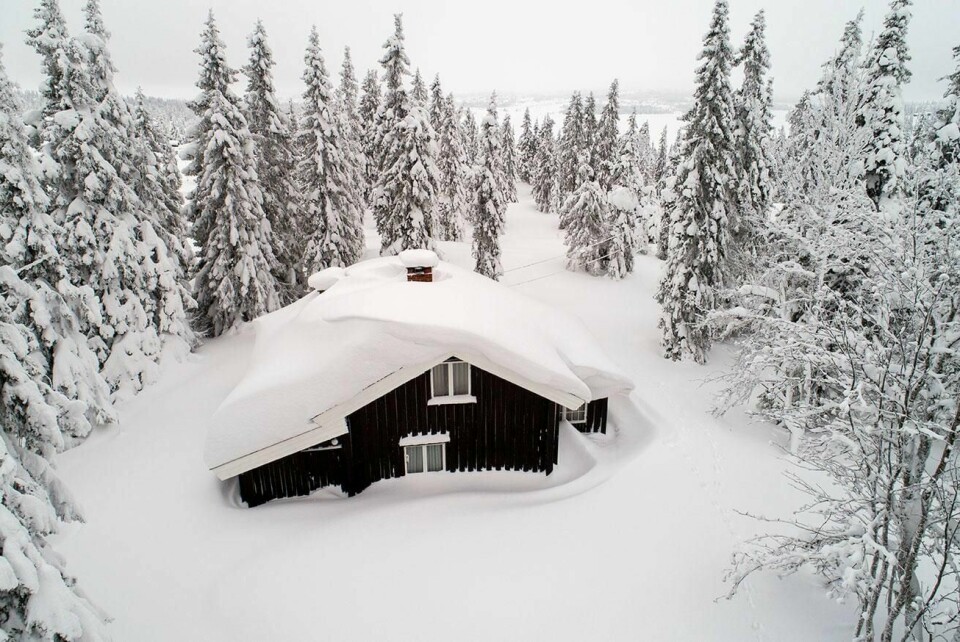 TUNGT: Dette bildet er fra en tidligere vinter. I år er det tung og våt snø på mange hyttetak i fjellet. Folk bør måke takene.