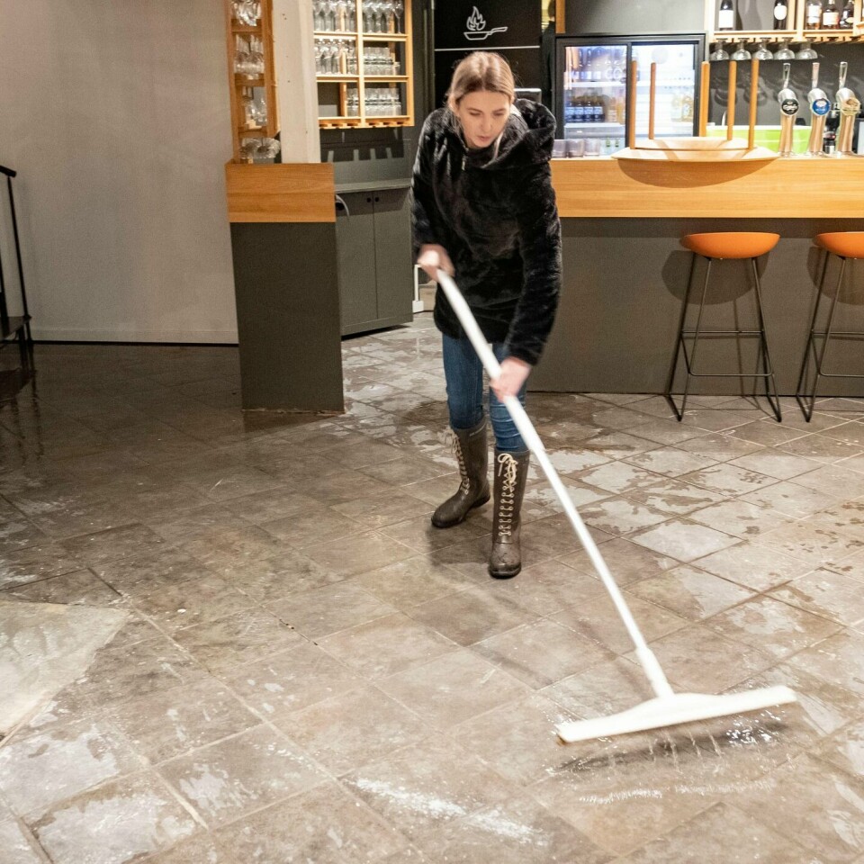 VANN: Vannet sto høyt langs kysten av Norge. Christina Weber prøver å få vannet ut av kafeen sin i Mandal.
