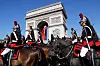 Bildet viser soldater som rir forbi Triumfbuen i Paris under paraden.