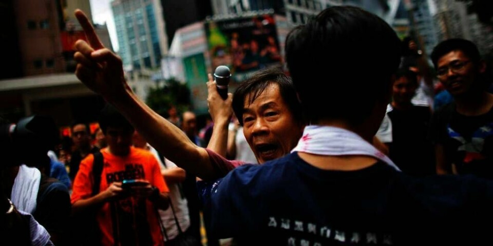 PROTEST: En demonstrant snakker for demokrati foran en bygning i Hongkong i Kina. Han krangler med en mann som støtter myndighetene i Beijing i Kina. Det er varslet flere store demonstrasjoner i Hongkong på nasjonaldagen onsdag.