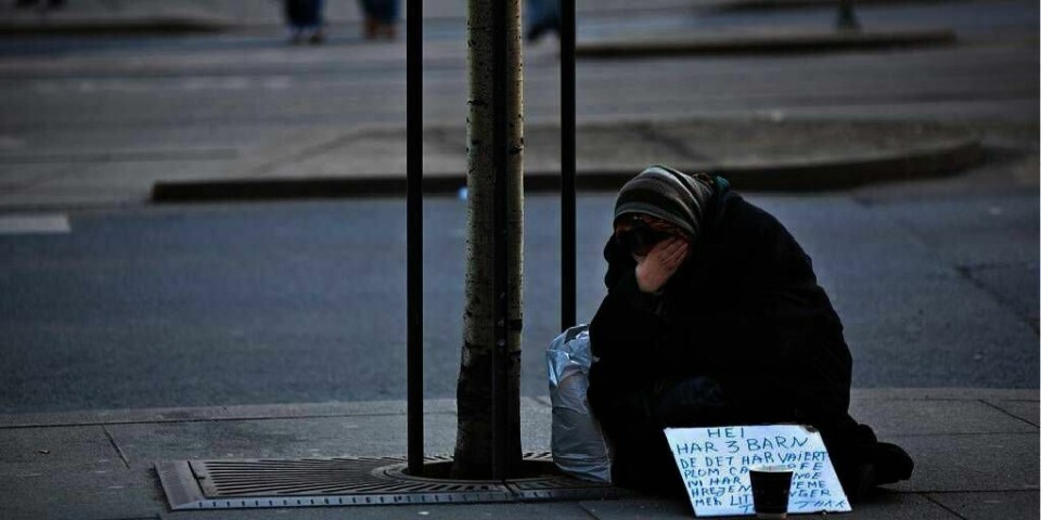 : Tigging  En kvinne tigger utenfor Royal Christiania Hotel i Oslo. På plakaten står det at hun tigger for sine tre barn.