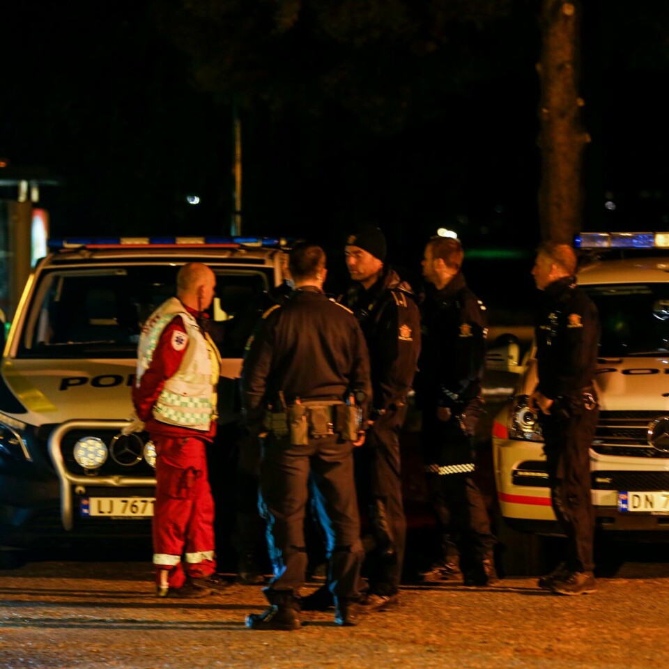 UKLART: Tirsdag sa politiet at en mann var knivstukket da han jogget i skogen. Det sa også flere vitner. Onsdag har politiet endret sin teori. Dermed er det uklart hva som faktisk har skjedd. Bildet er av politifolk som står foran flere politibiler mens de snakker. Det står også en ambulansesjåfør der. Det er mørkt ute. Foto: Trond R. Teigen / NTB