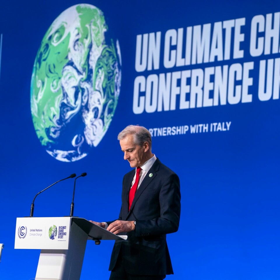 LØFTER: Statsminister Jonas Gahr Støre vil ha flere løfter om klima. Men det koster å redde jorda. Derfor må Norge tørre å ha en strengere politikk på miljø. Bildet er av Jonas Gahr Støre i dress. Hna står bak en talerstol og foran en blå vegg. På den er det bilde av jorda og det står at det er en konferanse om klimaendringer. Foto: Terje Pedersen / NTB