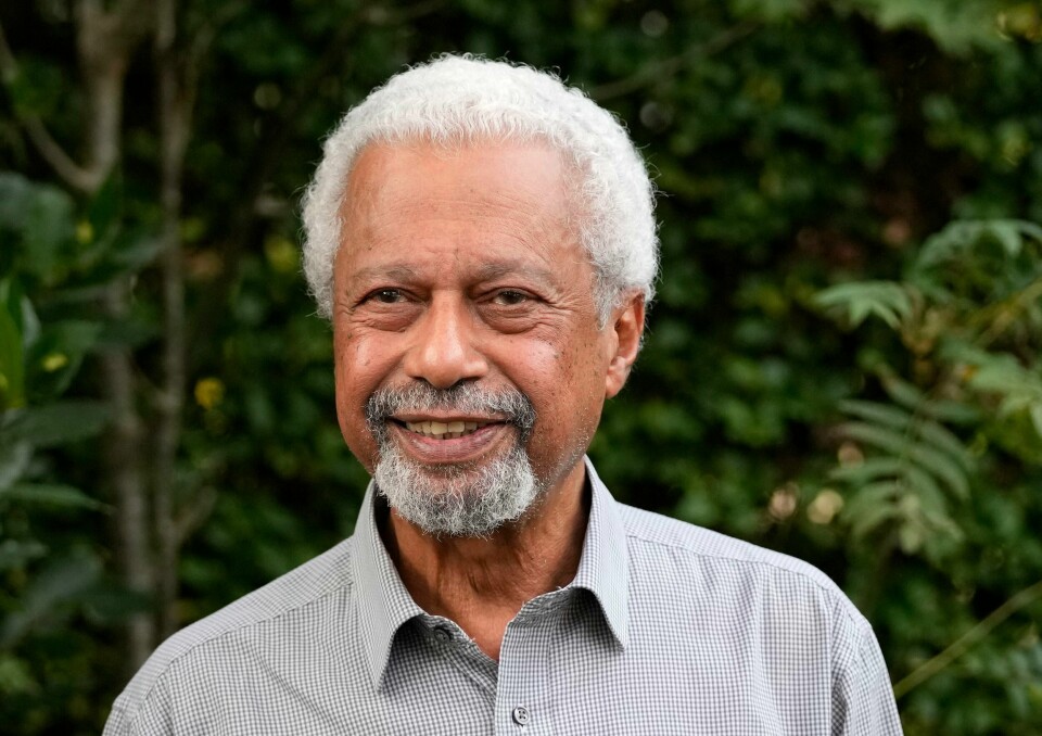 NORGE: Abdulrazak Gurnah skal til Norge. Han skal delta på litteraturfestival på Lillehammer i mai neste år. Bildet er av forfatteren Abdulrazak Gurnah. Bildet er tatt mens han står i skjorte foran en hekk. Foto: Frank Augstein / AP / NTB
