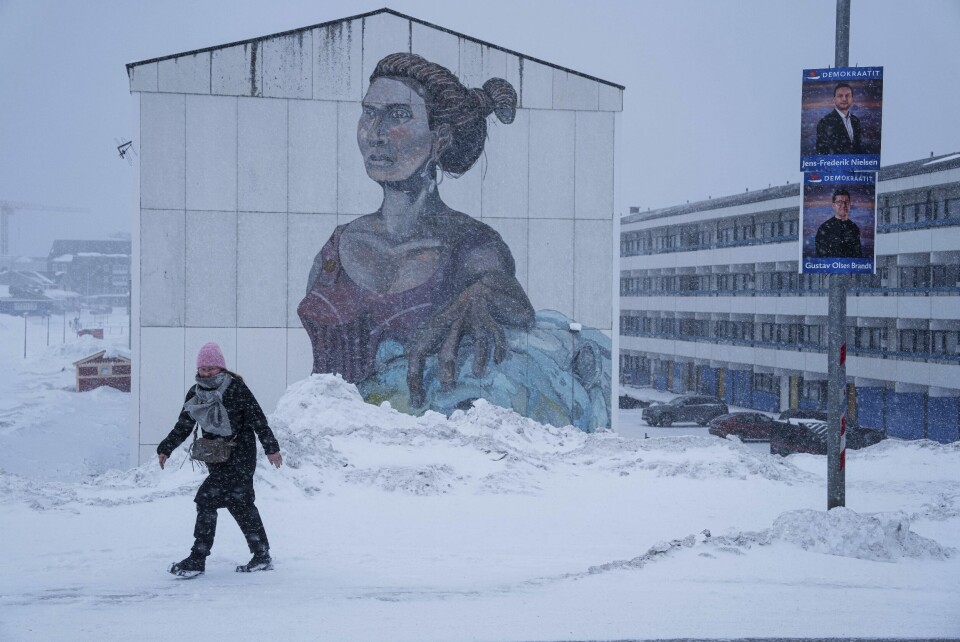 VALG PÅ GRØNLAND: En kvinne er ute i snøværet i Grønlands hovedstad Nuuk lørdag. På stolpen henger det valgplakater. Bildet viser en kvinne som er ute i snøværet i Grønlands hovedstad Nuuk lørdag. På stolpen henger det valgplakater. Foto: Jevhen Maloletka / AP / NTB