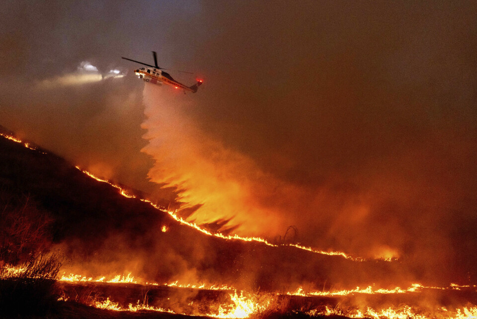 LOS ANGELES: Brannene fortsetter å herje i Los Angeles fredag. Minst ti mennesker er døde. Bildet viser et helikopter som tømmer vann over Kenneth-brannen i West Hills torsdag. Foto: Ethan Swope / AP / NTB