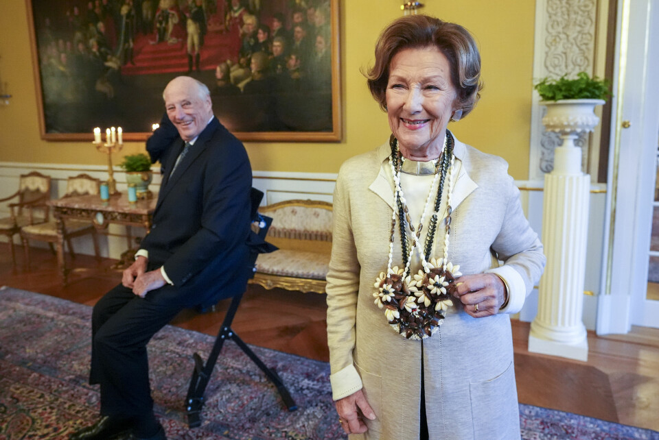 Dronning Sonja har blitt frisk og vender tilbake til offisielle oppgaver. Bilde av Dronning Sonja som smiler. Kong Harald på en krakk i bakgrunnen og ser blidt på henne.