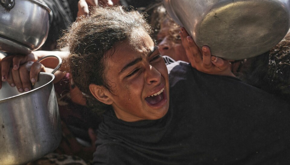 SULTER: 93 prosent av barna i Gaza er i kritisk risiko for sult. Bildet viser en ung palestinsk jente i matkø. Hun gråter intenst. Rundt henne står masse mennesker med skåler og gryter. De prøver også å få mat.