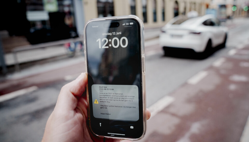 NØDVARSEL: Onsdag klokka 12 får folk over hele landet test av nødvarsel på mobilen. Varselet sendes ut som en test. En hånd holder en mobiltelefon som viser et nødvarsel på skjermen.