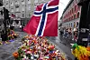 Bildet viser blomster og flagg dagen etter terrorangrepet i Oslo i 2022. Foto: Sergei Grits / AP Photo / NTB