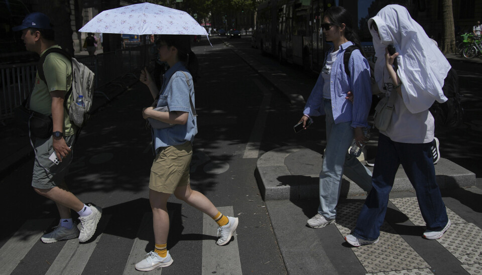 VARMT I PARIS: Folk beskytter seg mot varmen så godt de kan. Bildet er tatt i Paris i Frankrike. Bildet viser turister i varmen i Paris i Frankrike. Foto: Christophe Ena / AP Photo / NTB
