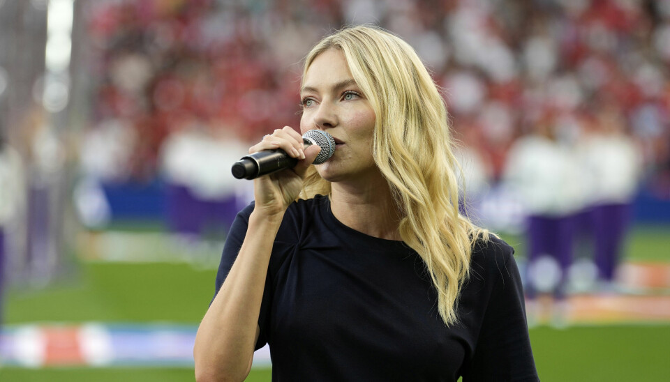FOTBALL-EM: Astrid S er beskyldt for plagiat etter at hun sang nasjonalsangen før kampen mellom Norge og Sveits. Astrid S holder en mikrofon og har på seg en svart kjole. Hun står på en fotballbane med masse publikum bak seg.