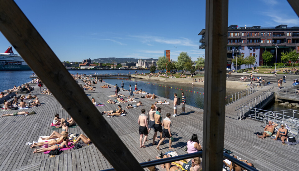 VÆR: Sør-Norge kan få opp mot 30 grader de neste dagene. Det er bare å ta fram badetøyet. Folk ligger i shorts og bikini på en stor brygge rett ved vannet. Det er blå himmel og sol.