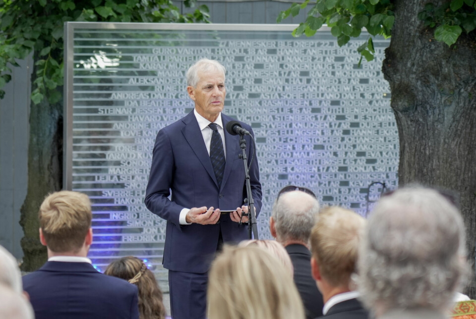 MINNESMERKE: mellom byggeplassene i Regjeringskvartalet står et minnesmerke. Her står navnene på alle de drepte. Bildet viser statsminister Jonas Gahr Støre. Han står foran minnesmerket og taler til folkemengden foran ham.