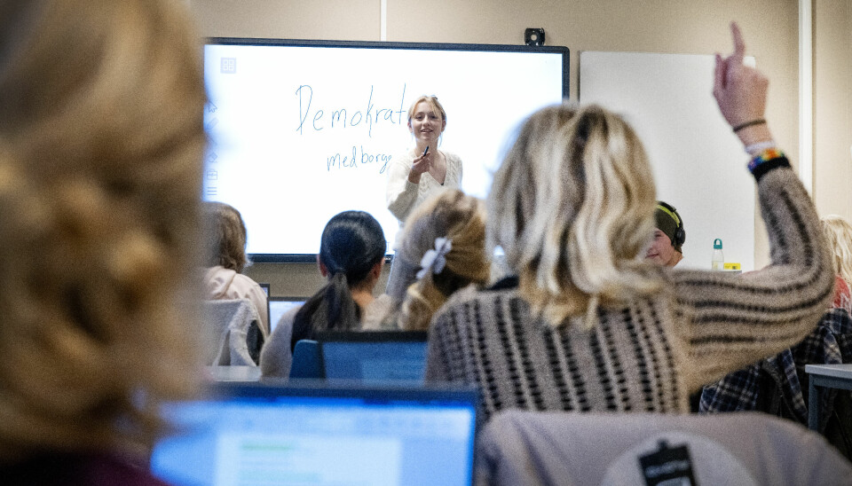 FRAVÆR: Det blir nye regler for fravær på videregående skole dette skoleåret. Bilde av kvinnelig lærer foran klasse og elev som rekker opp hånda. Foto: Gorm Kallestad /NTB