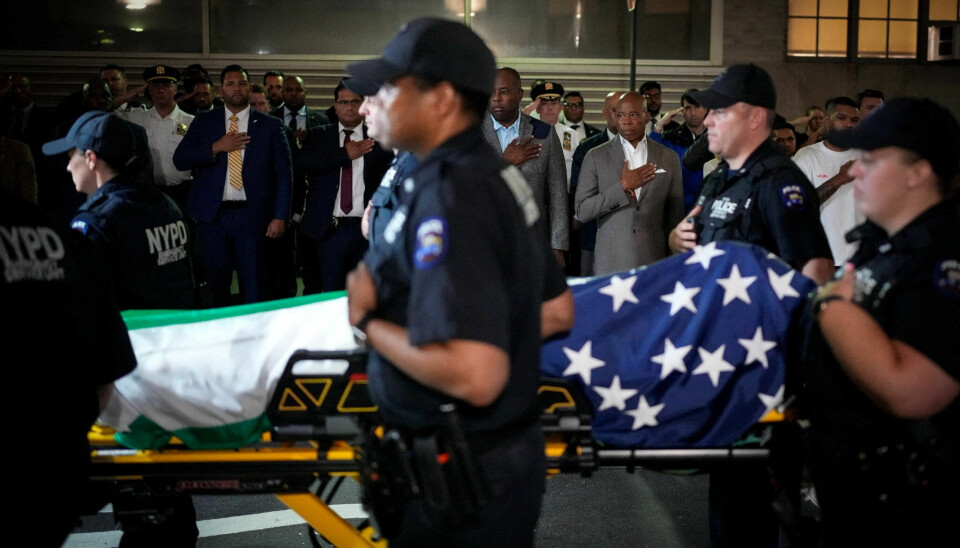 HEDRES: Sammen med ordfører, Eric Adams, tar kollegaene i New York Police Department farvel med Didarul Islam. Han ble drept i Manhattan mandag kveld. Bildet viser en båre som trilles inn i en ambulanse. På båren ligger Islam, dekket av et amerikansk og et bangladeshisk flagg. Flere politifolk er til stede. Det er også ordfører Eric Adams.
