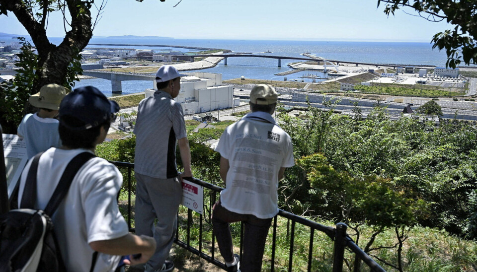 FRYKTER BØLGENE: Folk i Japan følger med på bølgene. De er klare til å evakuere om de skulle se noe uvanlig. Bildet viser fire japanske menn som står i høyden og følger med på bølgene som kan komme inn over byen.