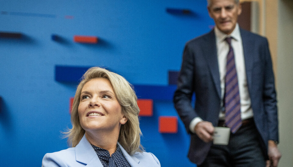 HEMMELIGHETER?: Statsminister og Ap-leder Jonas Gahr Støre og Sylvi Listhaug møtes til statsministerduell i Politisk kvarter på NRK. Listhaug har fortsatt ikke svart på om hun vil ha rollen som statsminister. Bildet viser Sylvi Listhaug som som smiler i forgrunnen. I bakgrunnen står Jonas Gahr Støre og ser på henne. Han er uklar i bildet.